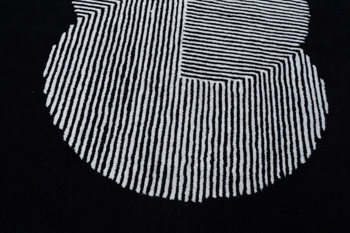 Clique Wool Rug in Pitch Black, a real close up of ivory lines filling a clustered form on a black hand tufted wool ground.