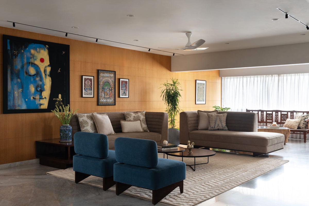 Insignia Wool & Silk Rug in a real living room, beside wood panelling, traditional paintings and blue armchairs.